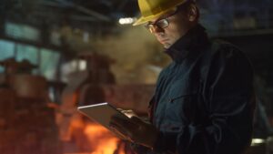 man in a hardhat using an ipad in an industrial setting